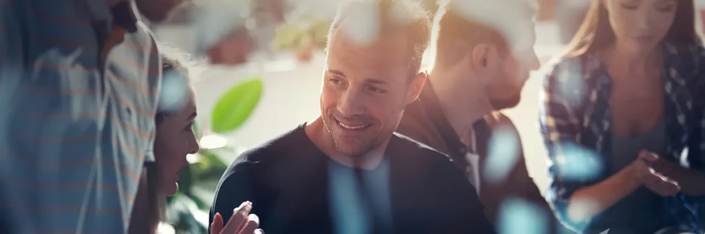 Junger Mann im entspannten Gespräch mit Finanzkollegen