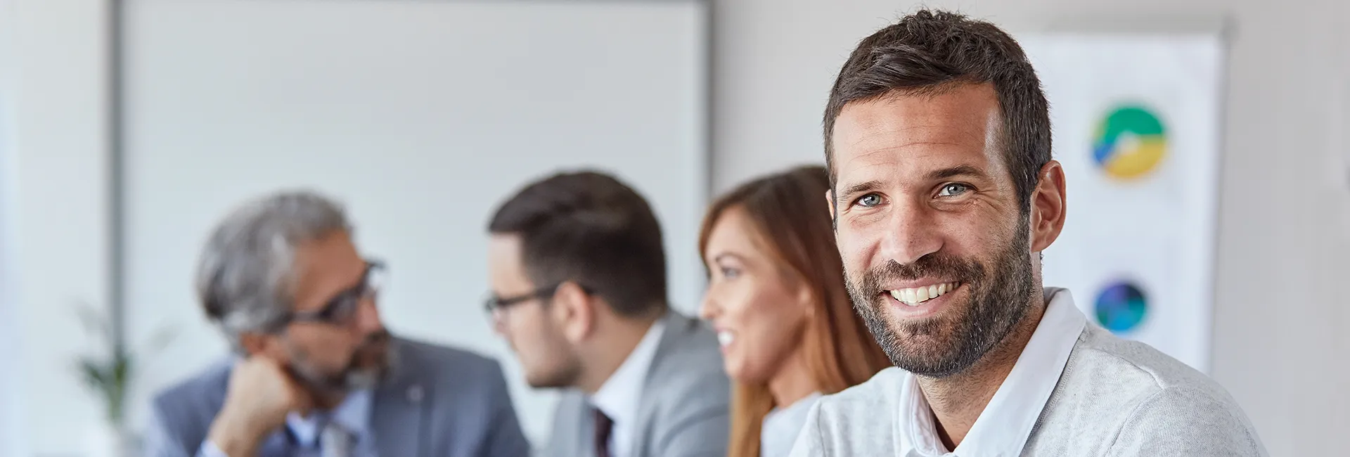 Produktportfolio Portrait eines Geschäftsmannes im Büro mit Kollegen bei einer Besprechung